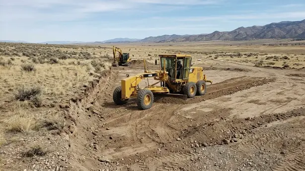 Motor grader leveling uneven ground during rural homesite site preparation in Costilla County, Colorado