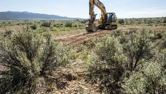 Native vegetation, exposed soil, rocks, and uneven terrain on rural Costilla County property